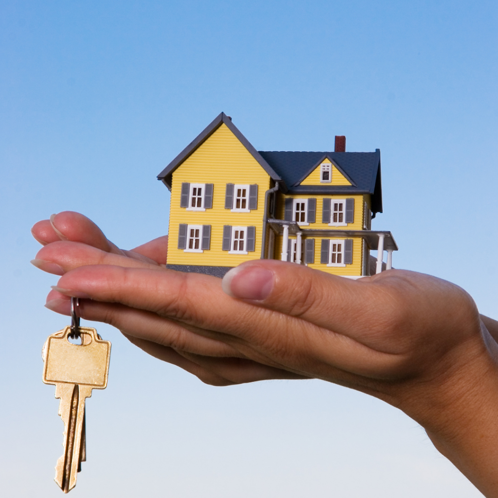 Maison miniature et clé dorée dans des mains, symbolisant l'immobilier et l'acquisition de propriété.