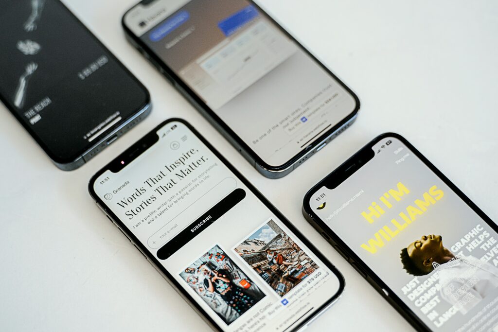 Photo de quatre smartphones posés sur une table blanche, affichant des écrans variés de sites web et d'applications mobiles. Chaque écran met en avant des designs modernes et épurés, soulignant l'importance de l'expérience utilisateur et de l'interface graphique. Cette image illustre le développement et la présentation de contenus numériques adaptés aux appareils mobiles.