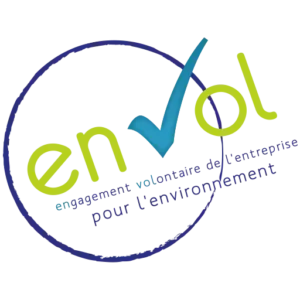 Logo du Label EnVol, qui signifie "Engagement volontaire de l'entreprise pour l'environnement". Ce label est représenté par un design circulaire bleu avec le texte "EnVol" en vert et bleu, accompagné d'une coche symbolisant la validation des pratiques écoresponsables. Ce label valorise les engagements des petites et moyennes entreprises en faveur de la durabilité environnementale.