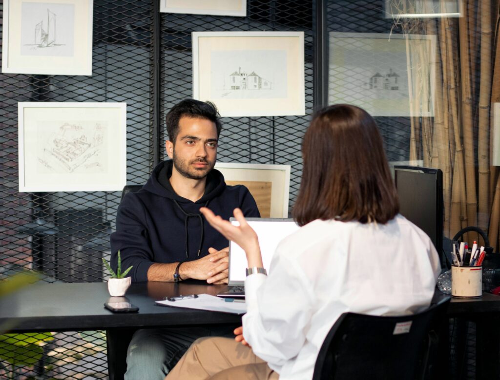 Un entretien de recrutement en face à face, avec un candidat attentif et une recruteuse qui pose des questions. Scène professionnelle illustrant la préparation et la réussite d’un entretien d’embauche.