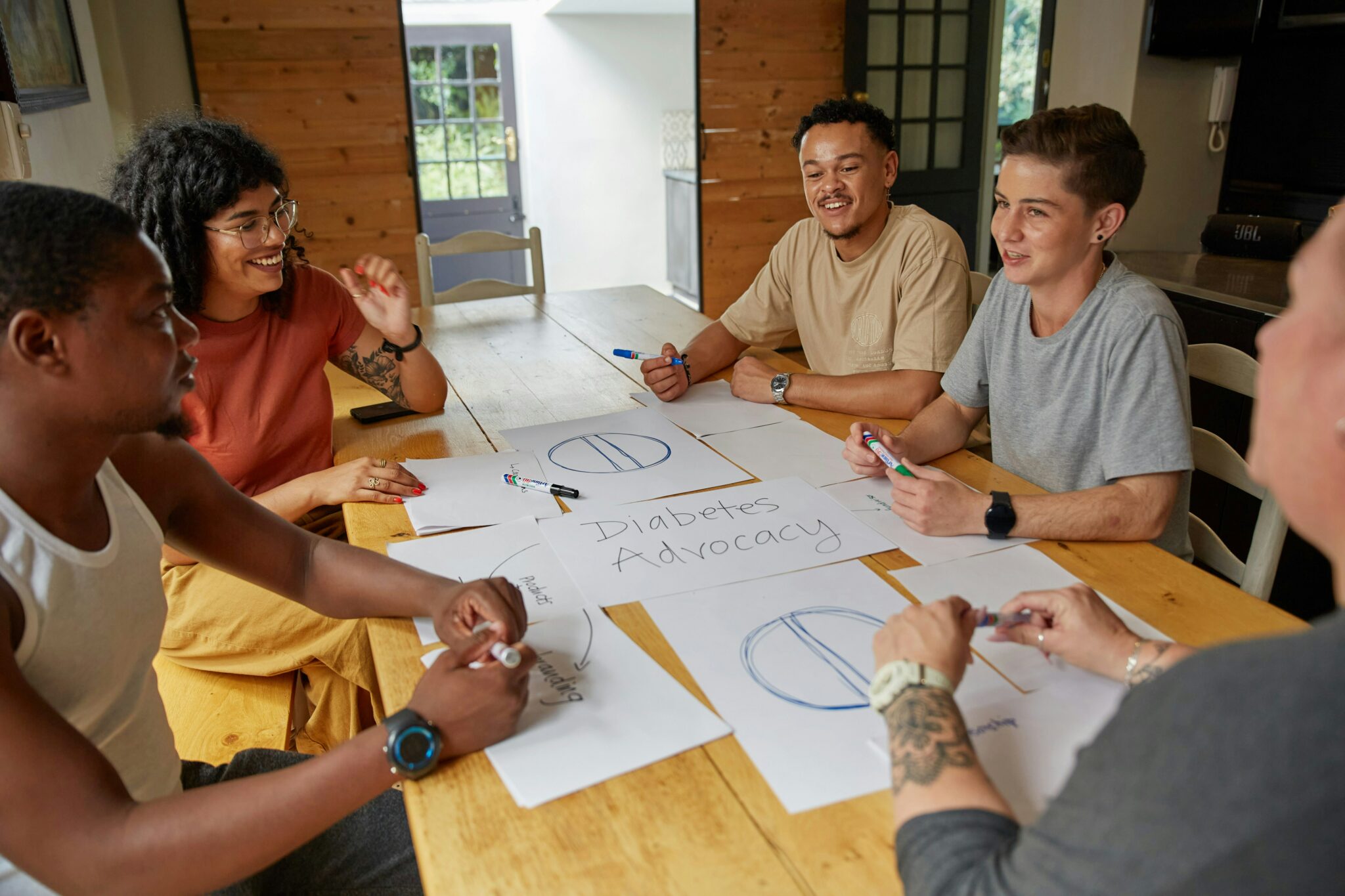 Des personnes collaborent autour d'une table en bois, participant à une session de brainstorming collectif. Chaque participant contribue activement, échangeant des idées et affichant une ambiance conviviale et motivante. Cette image illustre la créativité, la collaboration en équipe et l'importance des discussions structurées pour résoudre des défis ou développer des projets innovants.